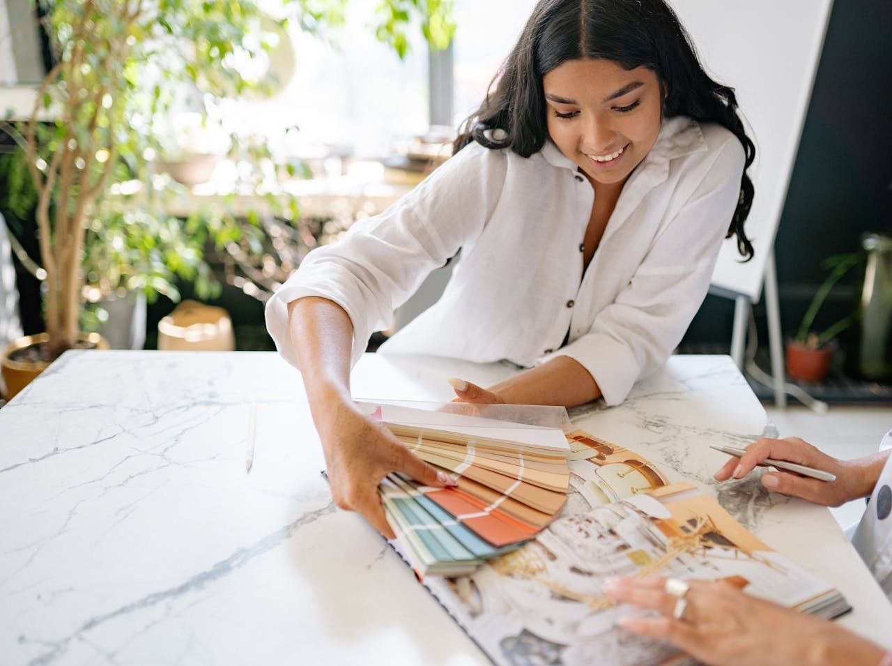 Smiling designer reviewing color palettes at a modern office desk, engaging in creative planning.